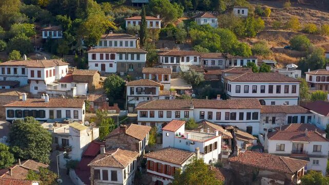 The charming atmosphere of Şirince village, drone camera. The unique architecture of whitewashed stone houses and red-tiled roofs offers a peaceful picture intertwined with lush green nature.