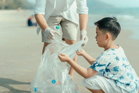 On the beach, a father and son carry bags to collect trash. Clean up the dirty sea or ocean and collect reusable plastic bottles. Garbage recycling.