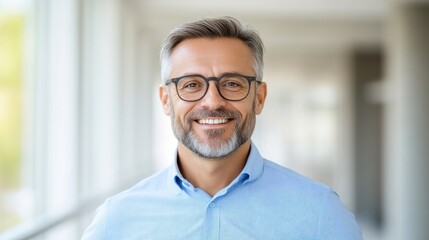 Fototapeta premium Smiling Man Graying Hair Professional Portrait Bright natural lighting, headshot view, confident expression, office backdrop, calm neutral tones, ideal for corporate websites.