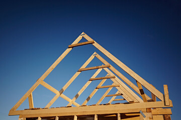 Wooden roof trusses against blue sky