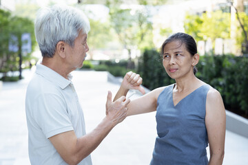 Old Asian senior woman ask an old man to stop smoking with thumb down gesture; concept image for no...