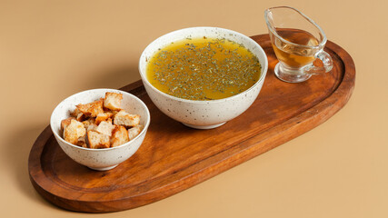 Chicken soup bowl with crackers on wooden tray