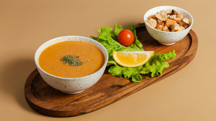 Lentil soup bowl with crackers on wooden tray