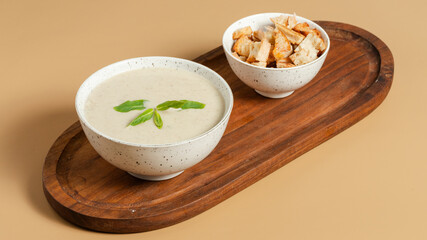 Mushroom soup bowl with crackers on wooden tray