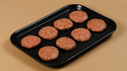 Raw cutlets on black tray