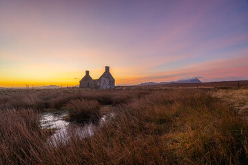 Sunrise behind the Moine House. A ruin of a stone cottage in the remote moorland in Sutherland in the far north of the Scottish Highlands.