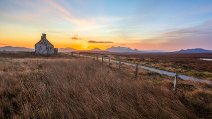 Sunrise behind the Moine House. A ruin of a stone cottage in the remote moorland in Sutherland in the far north of the Scottish Highlands.
