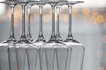 Upturned empty clean glasses on blurred background, closeup. Bokeh effect