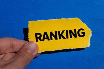 Ranking message written on ripped torn yellow paper piece on blue background. Conceptual ranking...