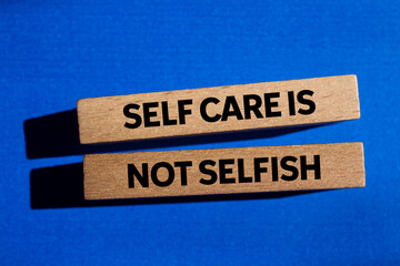Self care is not selfish message written on wooden blocks on blue background. Conceptual  self care...