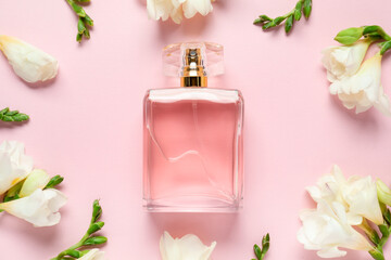 Bottle of perfume and beautiful flowers on pink background, flat lay