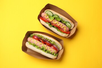 Tasty hot dogs on yellow background, flat lay