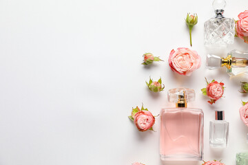 Flat lay composition with bottles of aromatic perfume and beautiful flowers on white background. Space for text