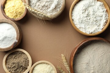 Frame made of different types of flour on light brown table, flat lay. Space for text