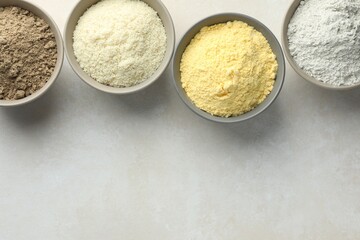 Different types of flour in bowls on light grey table, flat lay. Space for text