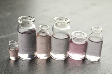 Open perfume bottles with aromatic essential oils on dark textured table, closeup