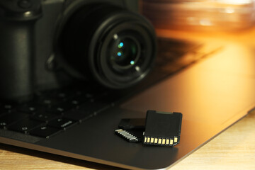 SD memory cards, laptop and photo camera on wooden table, closeup