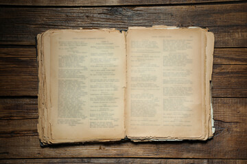 Open old book on wooden table, top view