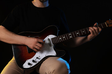 Man playing guitar on black background, closeup