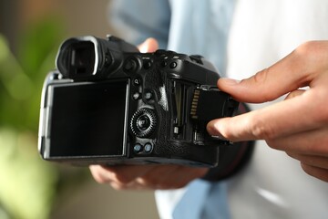 Man inserting SD memory card into photo camera indoors, closeup