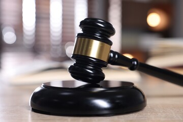 Judge's gavel and sound block on wooden table against blurred background, closeup