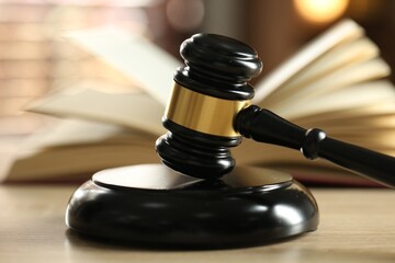 Judge's gavel and book on wooden table indoors, selective focus
