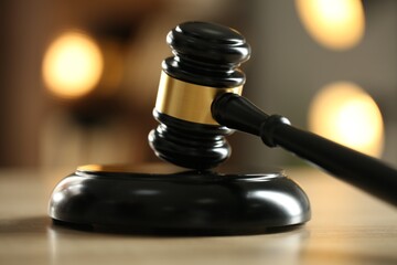 Judge's gavel on wooden table against blurred background, closeup
