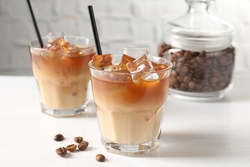Tasty iced coffee and beans on white table, closeup