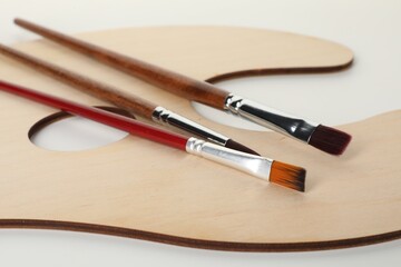Wooden palette and brushes on white background, closeup