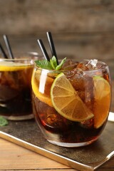 Refreshing Cuba libre cocktail with mint on wooden table, closeup