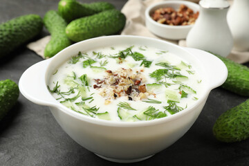 Fresh tasty cucumber soup and ingredients on black table, closeup