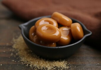 Tasty sweet caramel candies on wooden table, closeup