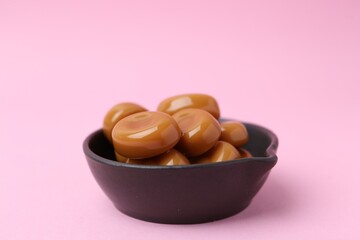 Tasty sweet caramel candies on pink background, closeup