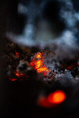 Smoldering embers in a campfire close-up, natural abstract background.