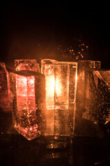 Crystal clear frosty textured natural ice block with cracks on black mirroring surface.