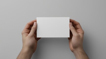 A blank white sheet of paper held by two hands against a matte gray background, capturing the precise shade tones of both the paper and the surface.