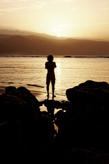 Anonymous male figure in silhouette on beach at sunset