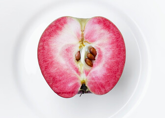 A sliced red apple with pink flesh on a white plate