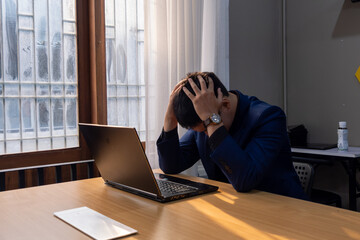 Stressed man experiencing frustration while working on his laptop in a modern office during...