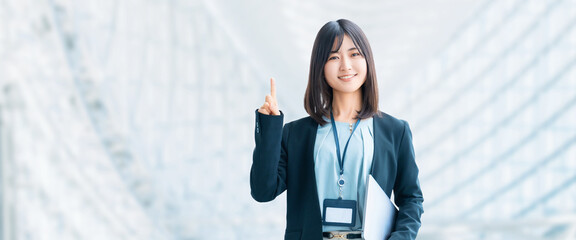 ノートパソコンを持って案内をする笑顔の女性・ビジネスウーマン