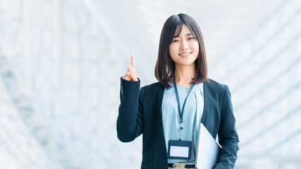 ノートパソコンを持って案内をする笑顔の女性・ビジネスウーマン