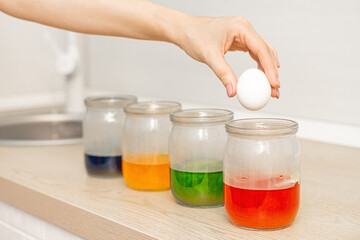 painting easter eggs at home, close-up. woman paints chicken eggs. preparation for the celebration of Easter. food coloring for easter eggs. hand drops egg into paint can