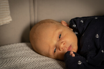 Baby lying on a soft blanket while gazing thoughtfully in a serene indoor setting during the day