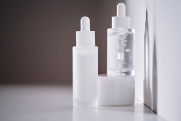 Two serums and a cream in a jar in the rays of the sun.