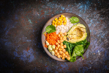 Poke bowl with spinach, avocado, corn, green salad, chickpeas, carrot and rice, dark background, top view. Concept of healthy eating, dieting