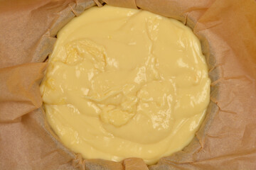 A top-down view of a light yellow vanilla and coconut cream cake filling set in a blue baking dish lined with parchment paper