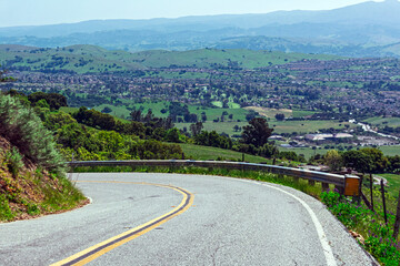 Scenic winding Quimby Road with guardrail curves downhill through green hills overlooking the...