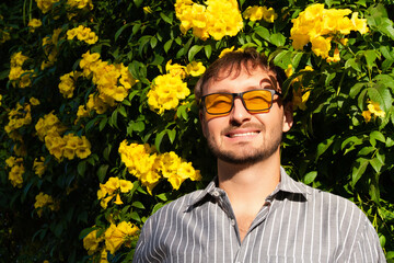 Fashion outdoor portrait of handsome man with short brown hair and beard wearing sunglasses with...
