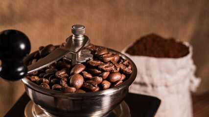 Fried Coffee Beans in a Manual Grinder. Preparation of Fresh Beverage Morning Coffee for Breakfast. Mill for Grinding with Bag of Coffee