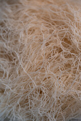 Delicate strands of kadaif are showcased in a lively kitchen, ready to be incorporated into a delicious traditional dessert. The warm lighting enhances the texture of the dough.